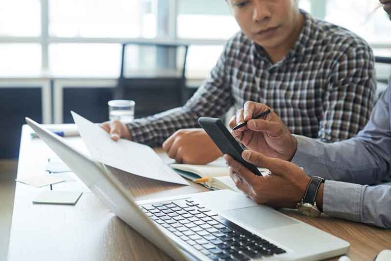 Two-people-at-desk-laptop-notes-reframe-solutions-blog-image